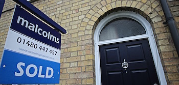 Malcolms sold board outside a house with a back door