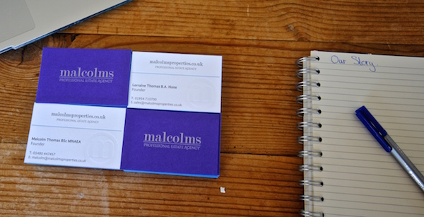 Malcolms Estate Agency's business cards next to notepad and pad