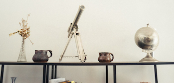 picture of a telescope, vase, globe and jugs on a table 