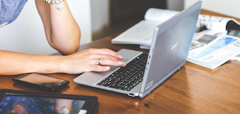 Lady with laptop searching Godmanchester with mobile phone and desk