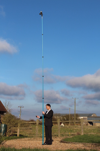 Man using elevated pole to take photo of house