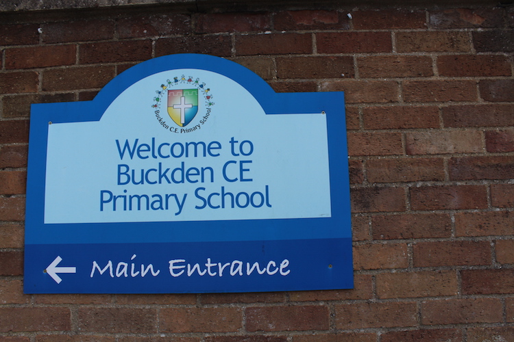 Sign on brick wall for Welcome to Buckden CE Primary School in blue