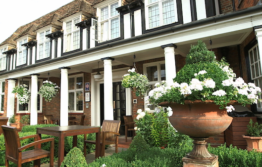 Entrance and gardens with table, chairs, flowers, hanging baskets at The George Hotel and Brasserie in Buckden